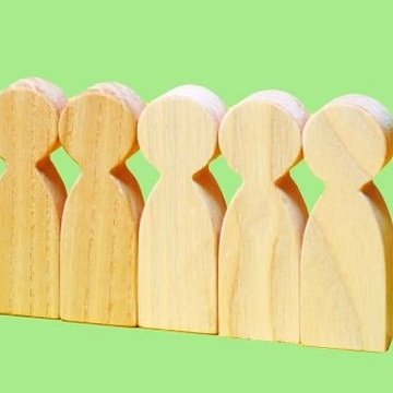 Five simple wooden figurines in front of light-green background