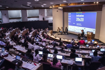 Conference scene showing the auditorium and the stage with panel members and big screen